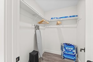 Ein kompakter Raum mit weißer Wand, einem Wäscheständer aus Holz, einem weißen Handtuch, einem blauen Koffer und einem Rollstuhl.