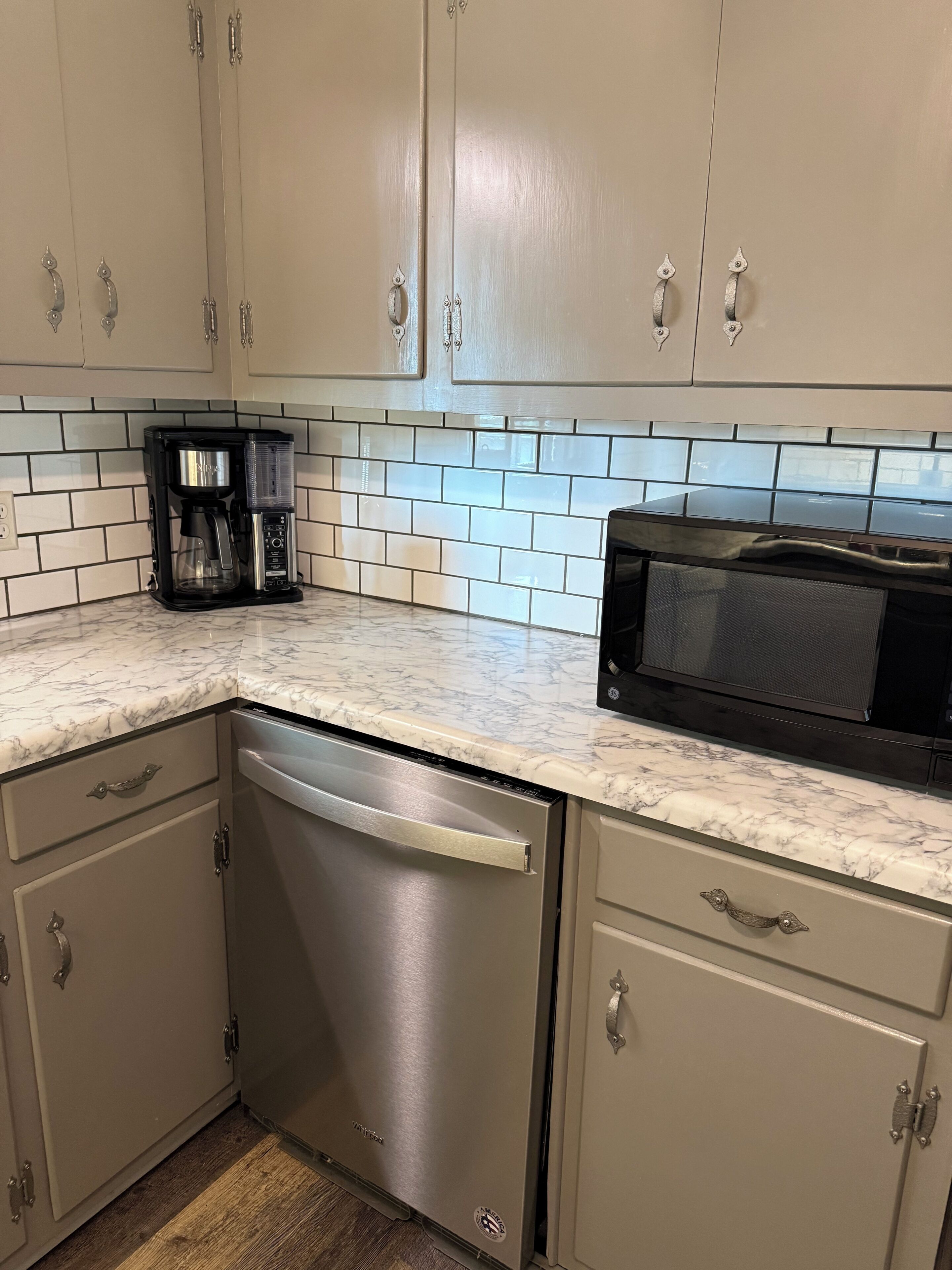 A kitchen with a dishwasher, a coffee maker, and a microwave.