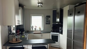 Eine moderne Küche mit einer zentralen Kochinsel, Barhocker, einem eingebauten Backofen und einem Edelstahl-Kühlschrank.