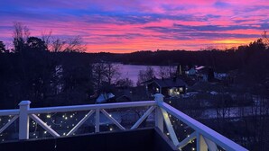 Ein Haus direkt am Wasser mit einer Terrasse mit Blick auf einen See, umgeben von Bäumen und Häusern.