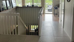 Ein geräumiger Flur mit einer Treppe zu einer Außenterrasse, einer Uhr an der Wand und Blick ins Grüne.
