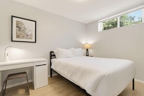 Ein Schlafzimmer mit einem Bett, einem Schreibtisch, einem Stuhl, einer Nachttischlampe und einem Fenster.