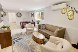 Ein Wohnzimmer mit Sofa, Sessel, Couchtisch und einem Essbereich mit Tisch und Stühlen.