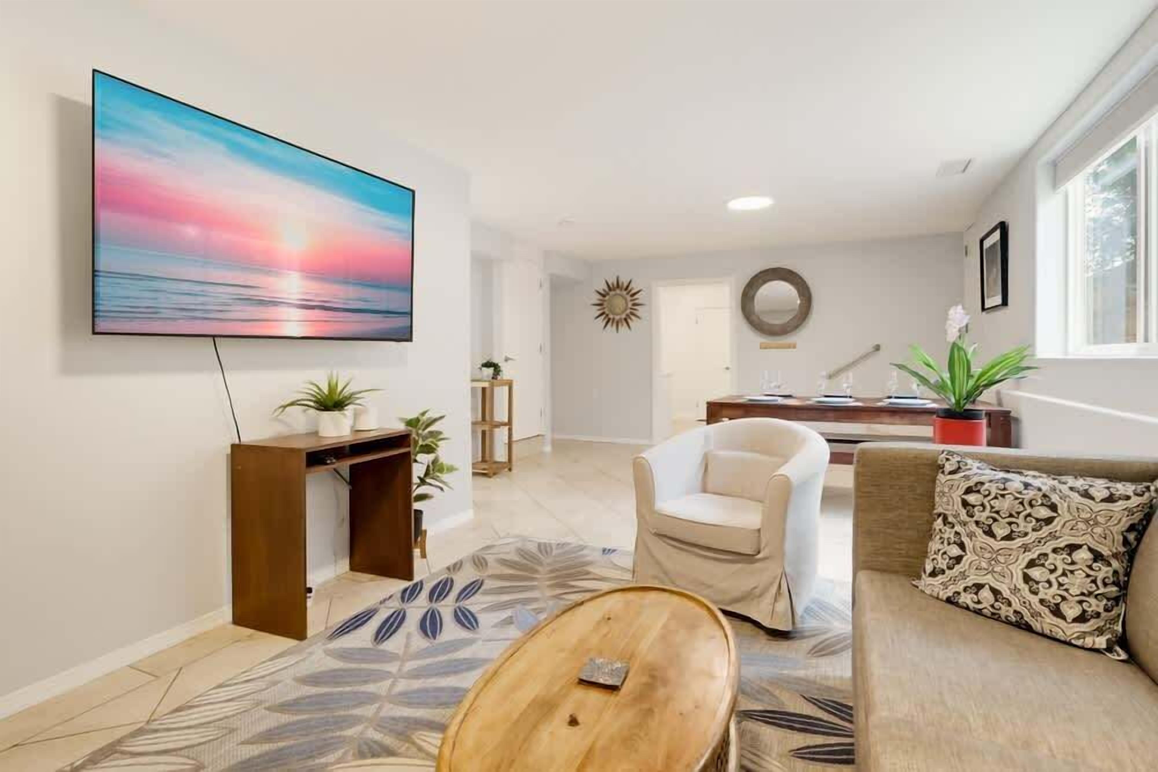 A living room with a flat-screen TV, a sofa, a coffee table, and a patterned rug.