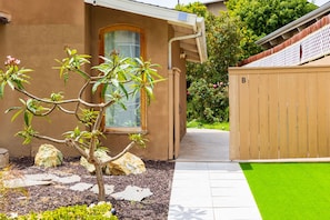 Ein Wohnhaus mit gepflegtem Garten, Holzzaun und gepflastertem Weg.