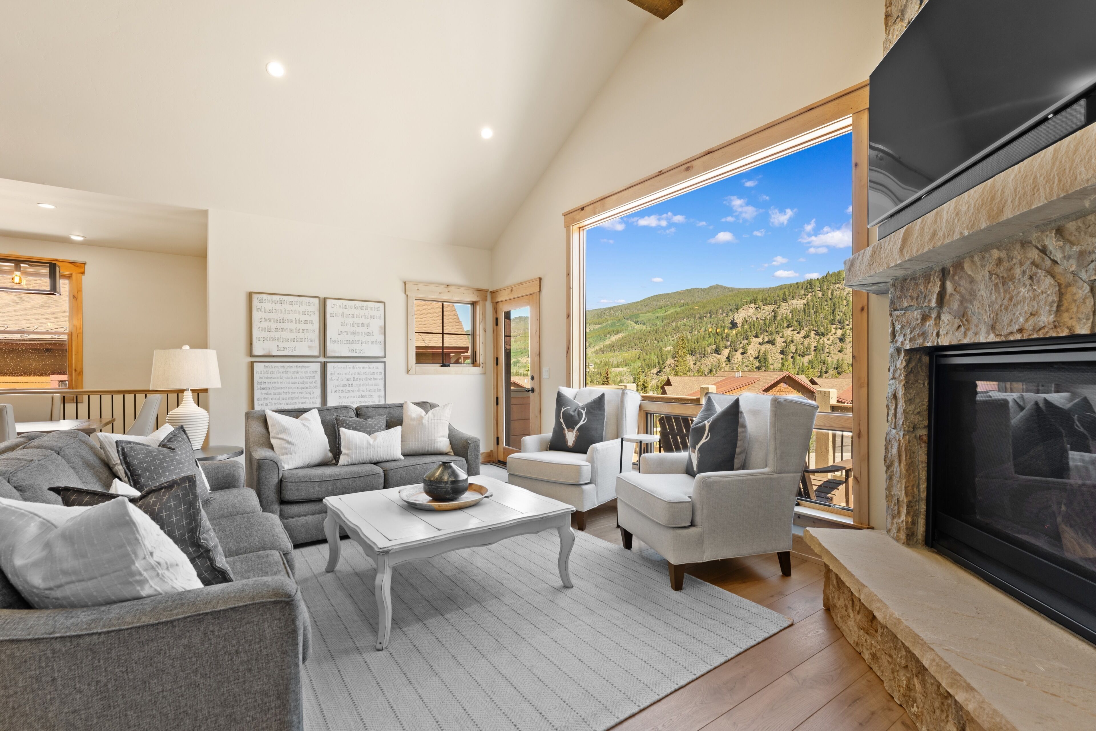 A spacious living room with a fireplace, comfortable seating, and a large window offering a view of the outdoors.