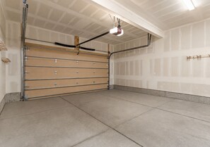 A garage with a large, closed garage door, a ceiling-mounted projector, and a concrete floor. - Perfect Family Getaway: 4BR with Stunning Alpine Views (Keystone)