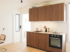 Eine moderne Küche mit Holzschränken, einem Einbauofen und einer Arbeitsplatte mit Kaffeemaschine und Toaster.