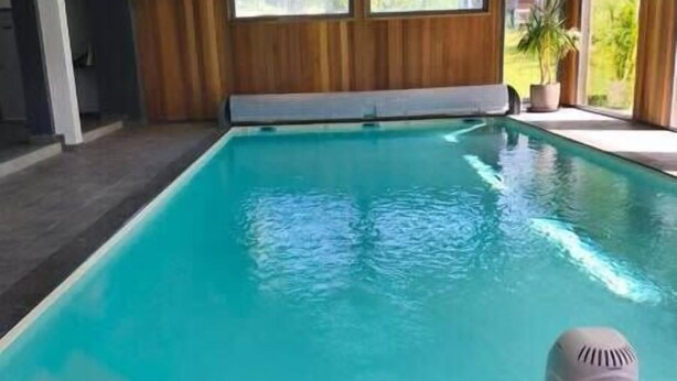 Ein Hallenbad mit klarem Wasser, Holzwänden und einem Fenster, das natürliches Licht hereinlässt.