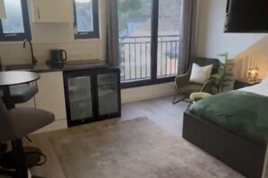A compact room with a kitchenette, a dining area, a sofa, and a window with a view of the outdoors. - Studio - Sleeps 2- Parking (Sheffield)