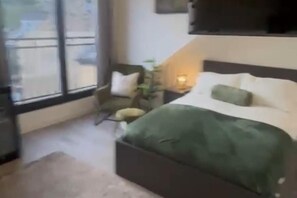 A bedroom with a bed, a chair, a bedside table, and a window. - Studio - Sleeps 2- Parking (Sheffield)