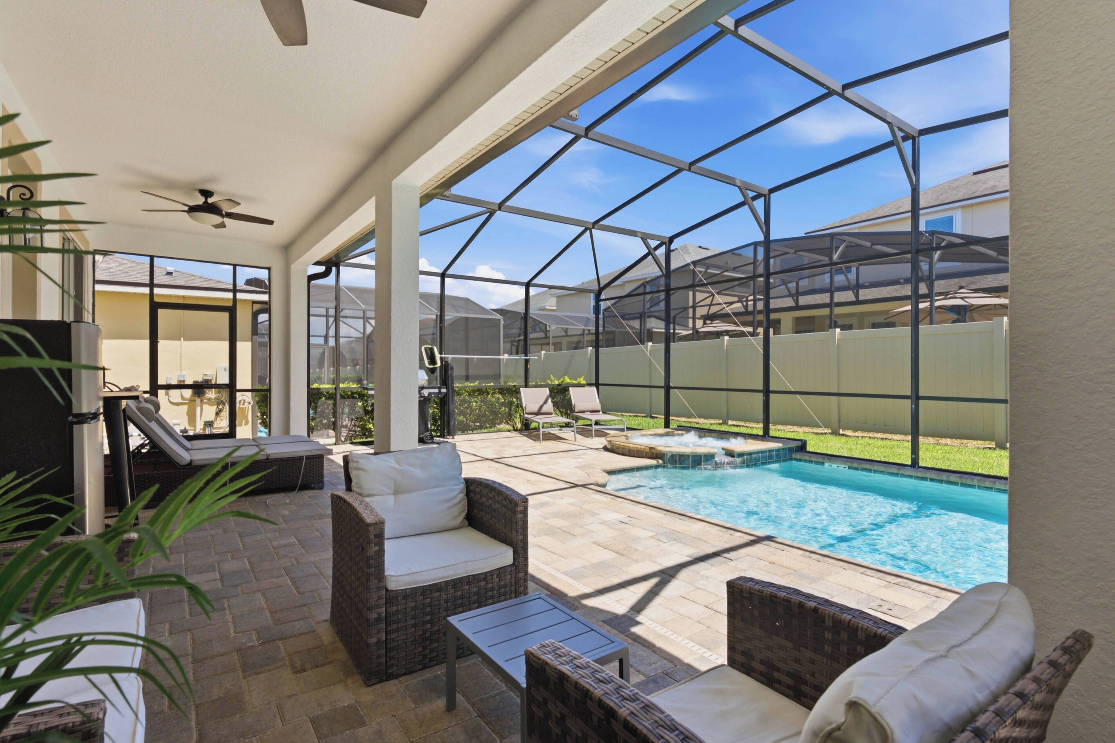Un espacio al aire libre cubierto con piscina, mobiliario de patio y vistas al jardín.