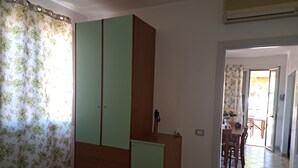 A bedroom with a wardrobe, a bed, and a view into a dining area. - The Residences 6 (Marina di Modica)
