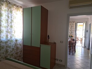 A bedroom with a wardrobe, a bed, and a view into a dining area. - The Residences 6 (Marina di Modica)