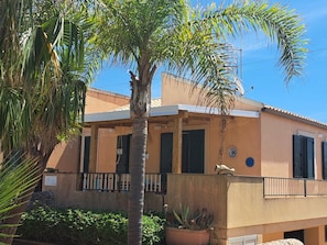 A building with a balcony, a palm tree, and a potted plant. - The Residences 6 (Marina di Modica)
