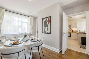 A dining area with a round table, chairs, and breakfast items. - Detached Coastal Home - Walk to Beach - Sleeps 4 (Overstrand)