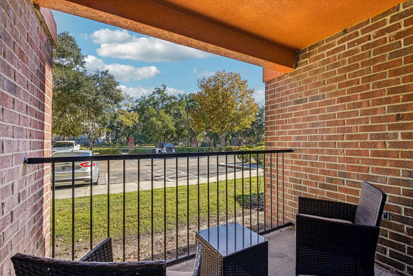 A balcony with a view of a parking lot and trees.
