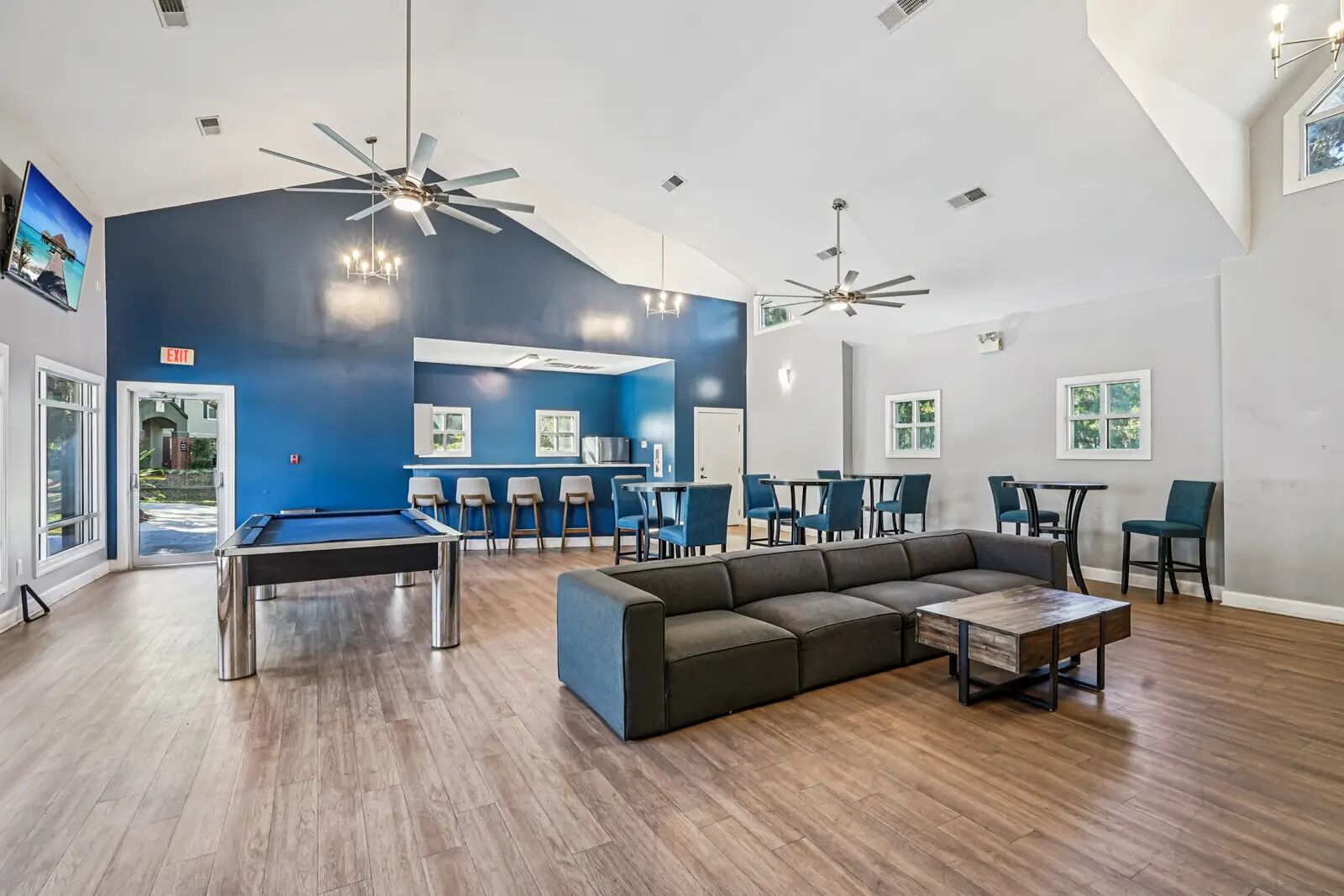 A spacious indoor area with a pool table, a sectional sofa, and multiple ceiling fans.