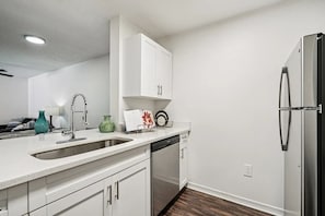 A modern kitchen with white cabinetry, stainless steel appliances, and a dishwasher.