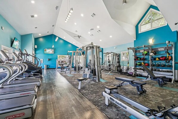 A gym with treadmills, weight machines, and a variety of weights and exercise balls.