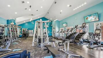 A gym with various exercise equipment, including treadmills, weight machines, and free weights.