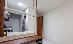 A kitchen with a countertop, cabinets, and a refrigerator. - Lindo estúdio em condomínio no Sudoeste (Águas Claras)