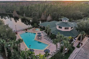 Ein Resort mit Swimmingpool, Liegestühlen und einem Gebäude mit markanter Dachkonstruktion.