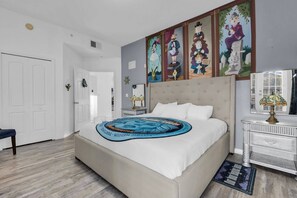 Ein Schlafzimmer mit einem großen Bett, einem Nachttisch, einer Lampe und einem Fenster mit Jalousien.
