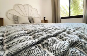 A bed with a patterned blanket, a white headboard, and a nightstand with a lamp. - Oasis Dunas Canary House Deluxe by B-Rent – Luxury & Comfort in Corralejo (Corralejo)