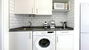 Eine kompakte Küche mit Waschmaschine, Kaffeemaschine und Mikrowelle.