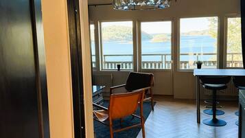 A room with a view of a lake, a wooden floor, a dining table, and a chair.