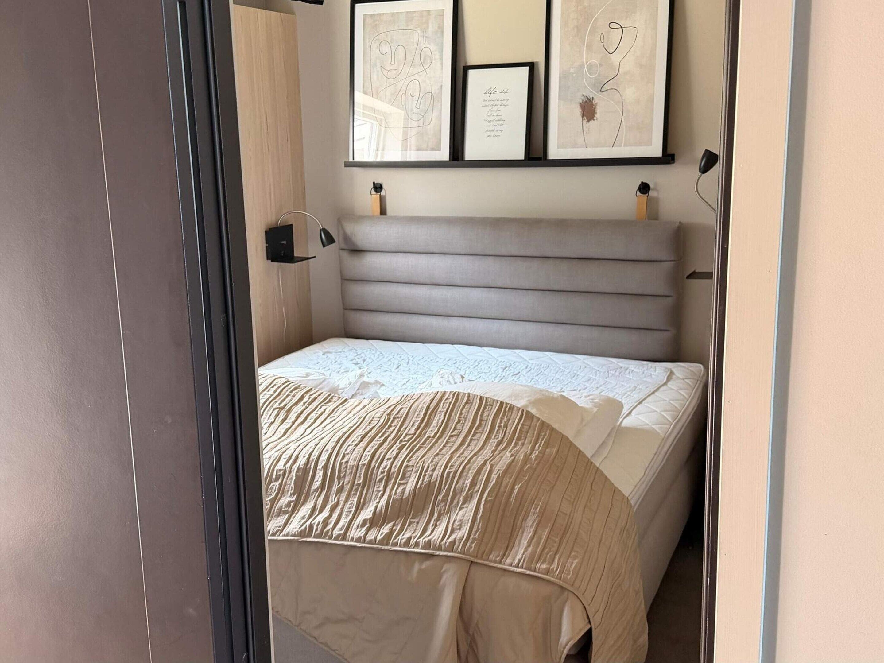 A bedroom with a bed, a headboard, a bedside table, and wall-mounted artwork.
