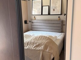 Un dormitorio con cama, cabecera, mesita de noche y una obra de arte colgada en la pared.