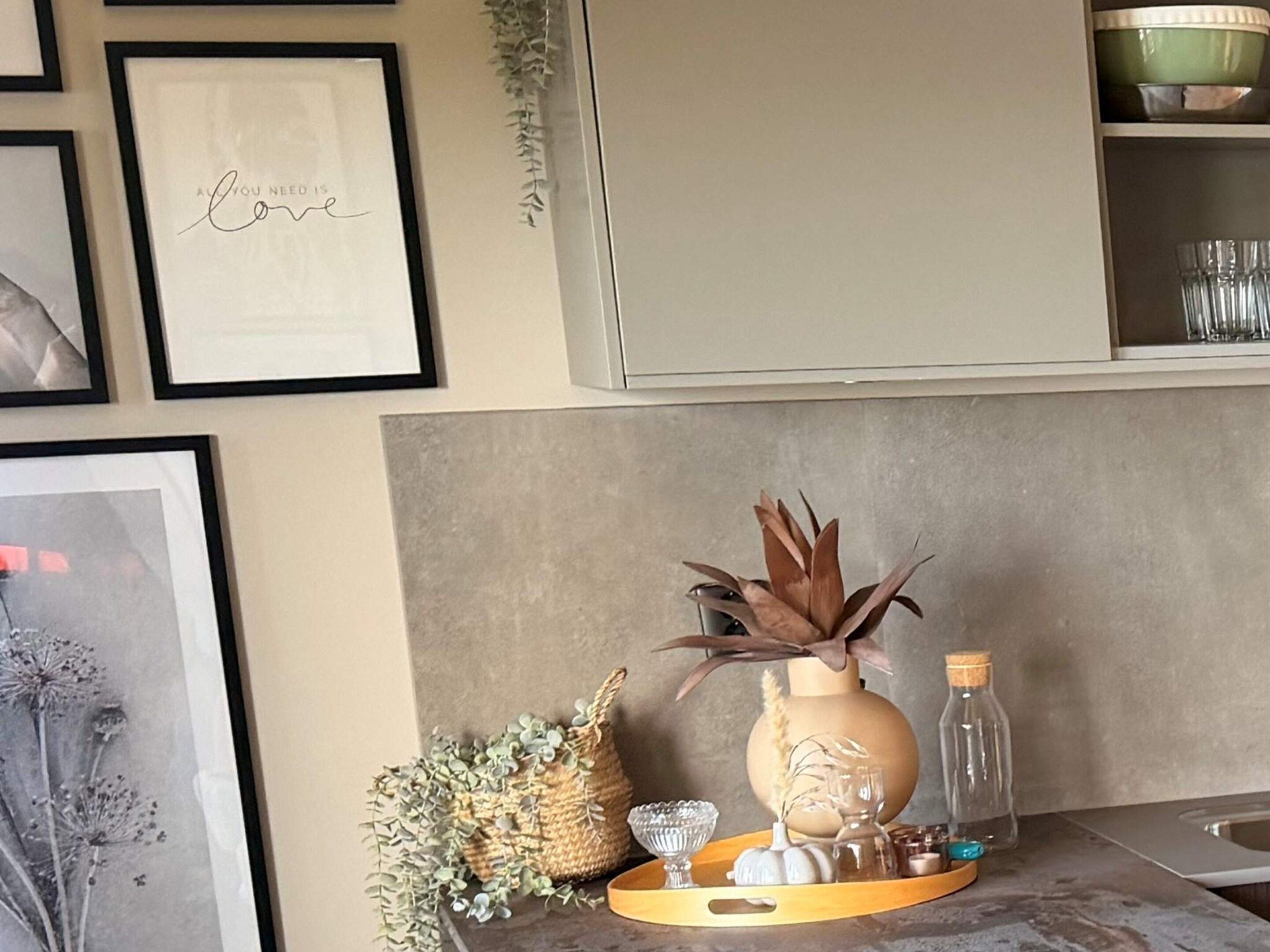 A kitchen counter with a tray holding a vase, a bottle, and decorative items.