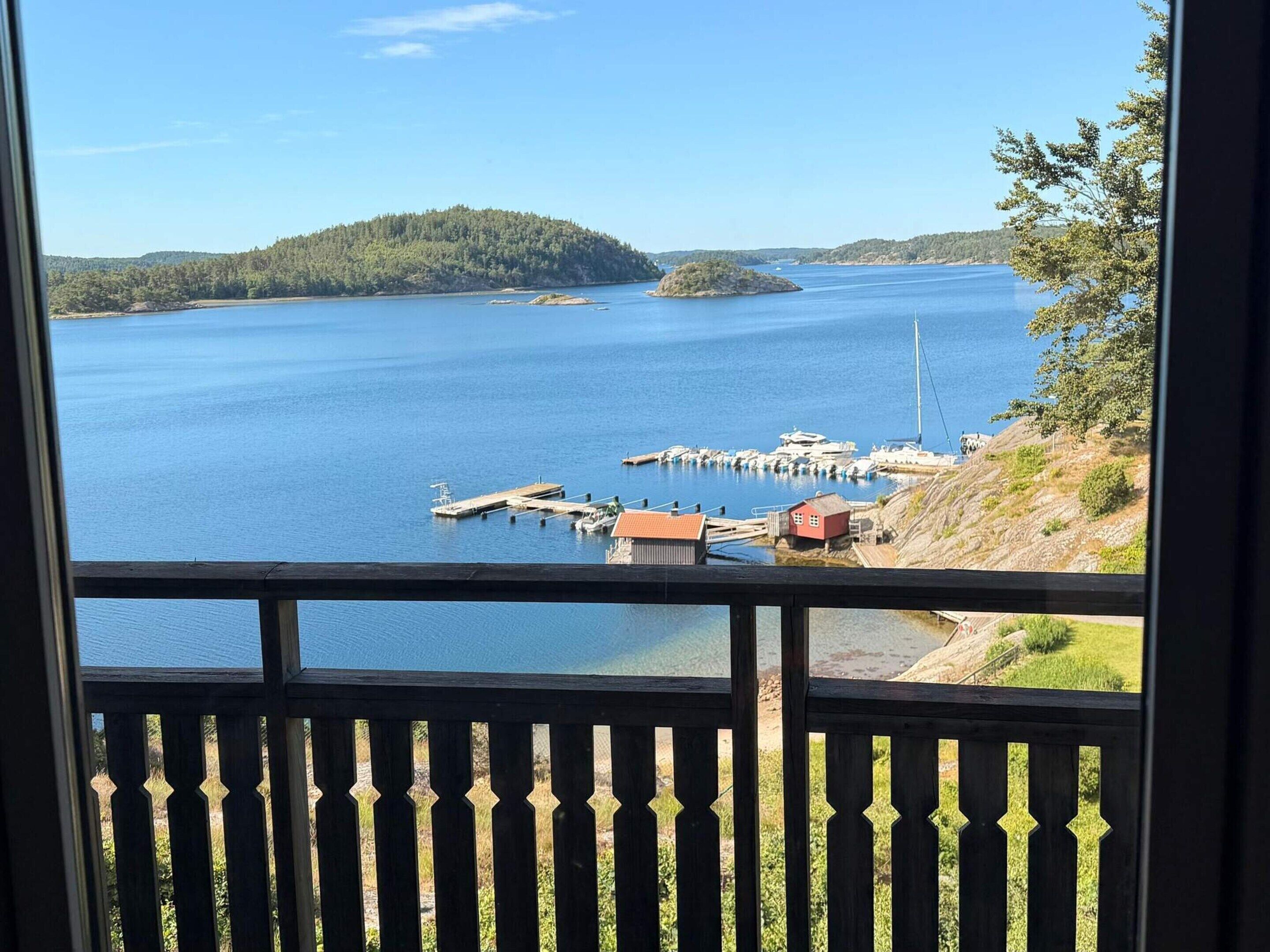 A view of a calm lake with a dock and a small island in the distance.