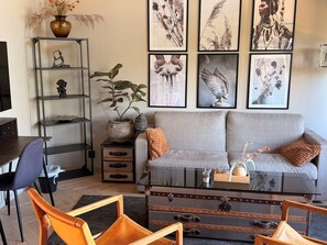 A living room with a sofa, coffee table, and chairs. There are framed artworks on the wall and a plant on a shelf. - 5 Star Holiday Home in Uddevalla (Uddevalla)