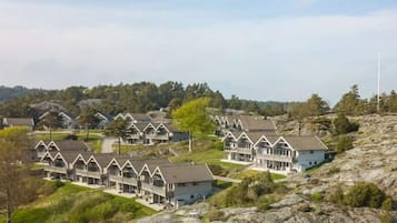 A cluster of modern, multi-story buildings with a uniform architectural style, situated on a rocky hillside with a backdrop of trees and a clear sky.