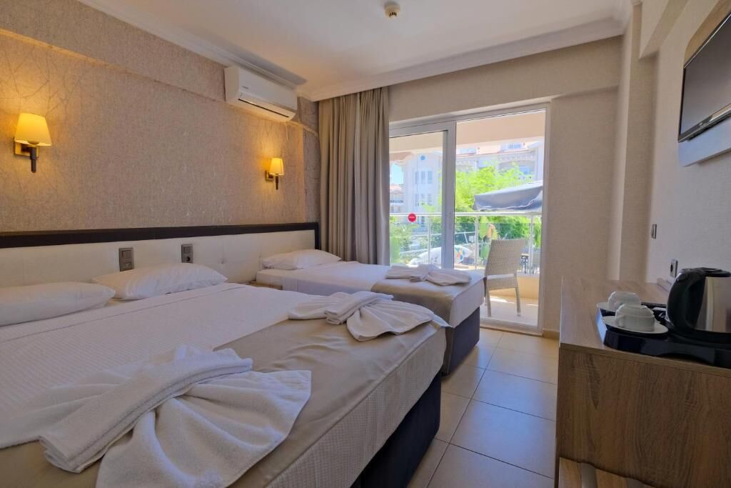 Une chambre d’hôtel avec deux lits, un balcon offrant une vue et un téléviseur fixé au mur.