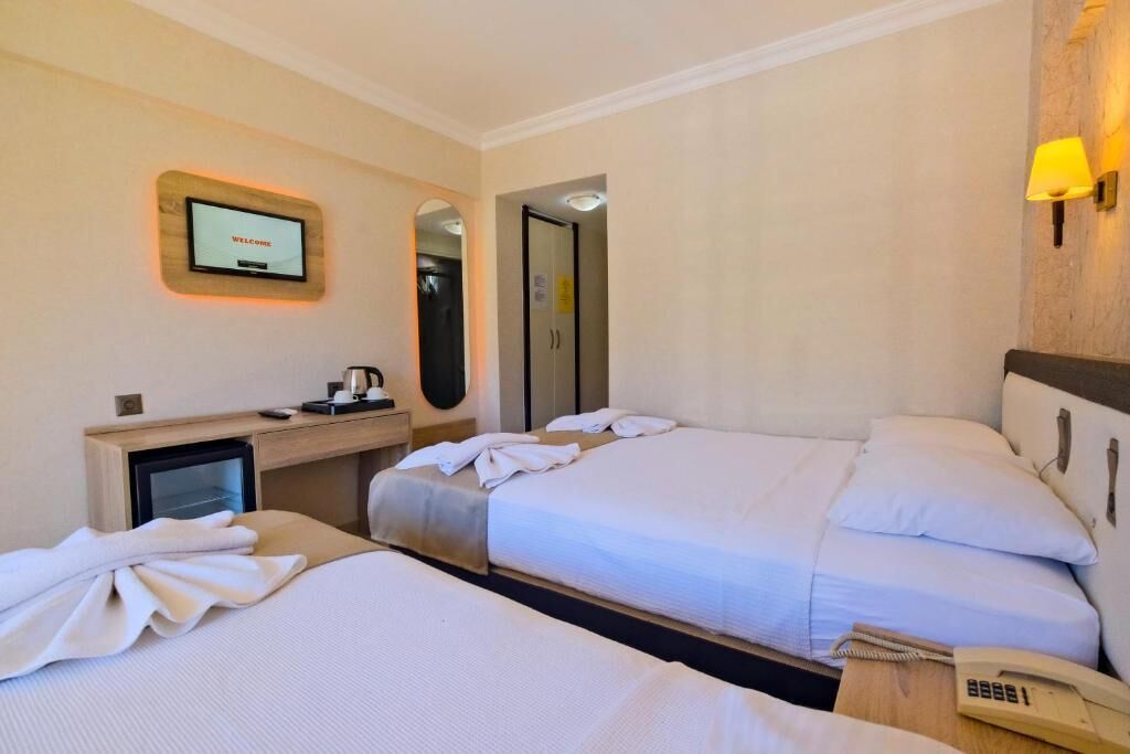 A hotel room with two beds, a desk with a computer, a TV, and a phone.