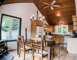 Eine geräumige Küche mit Holzausstattung, einem Esstisch mit Stühlen, einer Kandelaber und einem Deckenventilator.