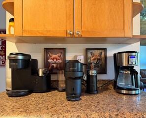 Eine Küchenarbeitsplatte mit verschiedenen Kaffeemaschinen und einem Bilderrahmen mit einem Fuchs.