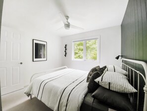 Ein Schlafzimmer mit Bett, Deckenventilator, Fenster und Tür.