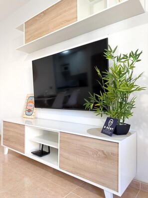 Un meuble de divertissement moderne, doté d’un téléviseur à écran plat, d’une petite plante et d’un tableau encadré.