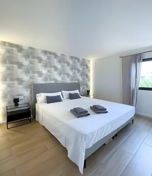 Een moderne slaapkamer met een groot bed, een nachtkastje en een wand met een structuur.