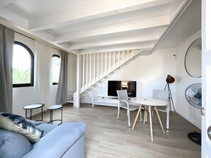 Een moderne woonruimte met een trap, een eethoek en een bank.