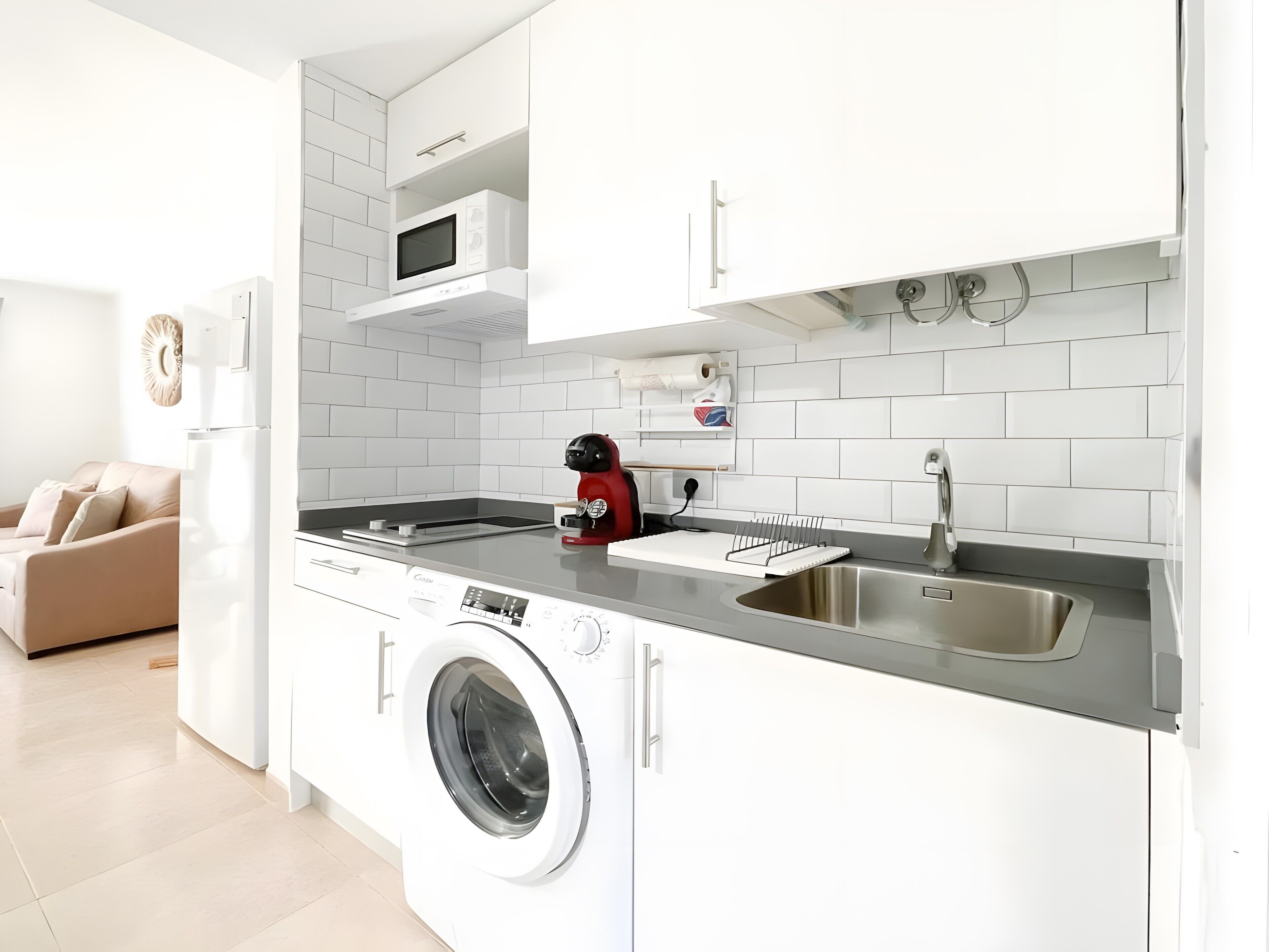 A compact kitchen with a built-in washing machine, a microwave, and a sink.