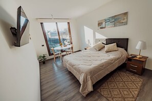 A bedroom with a bed, bedside table, lamp, and a view through a glass door. - Executive Office · Gym · Coworking Space · Cumming Metro Station (Santiago)