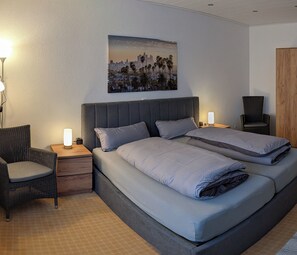 Ein Schlafzimmer mit einem Bett, zwei Nachttischen, einem Sessel, einer Nachttischlampe und einem Bild an der Wand.
