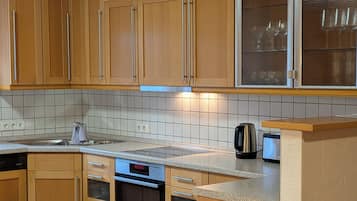 Eine moderne Küche mit Holzausstattung, Backofen, Kaffeemaschine und einem Essbereich mit Tisch und Stühlen.