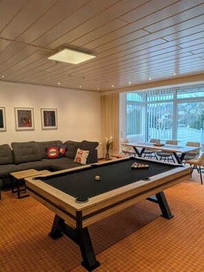 A modern living room with a pool table, a sofa, and a dining area with chairs. - Dein riesiges Apartment für Familien und Freunde bis 12 Personen (Reichartshausen)